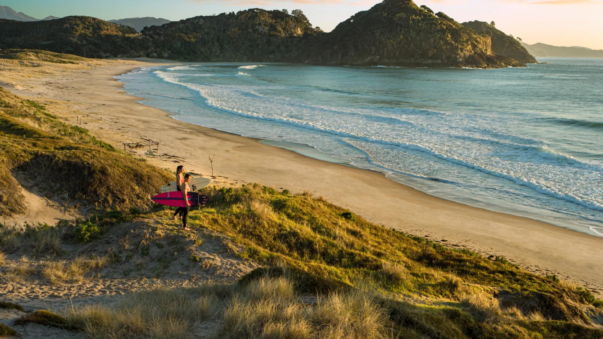 Twee surfers met hun surfboards bij Medlands Beach, Great Barrier Island