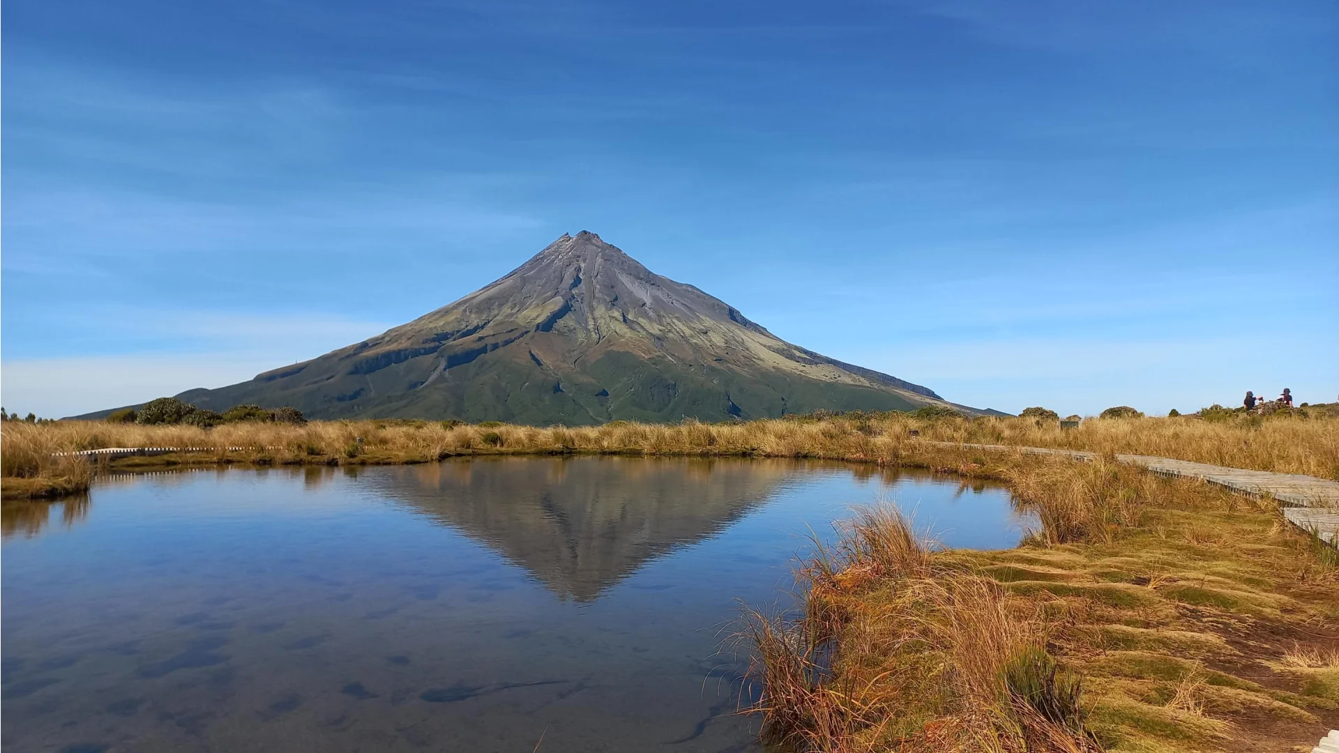 Mount Taranaki in de zon met de weerspiegeling in de tarns