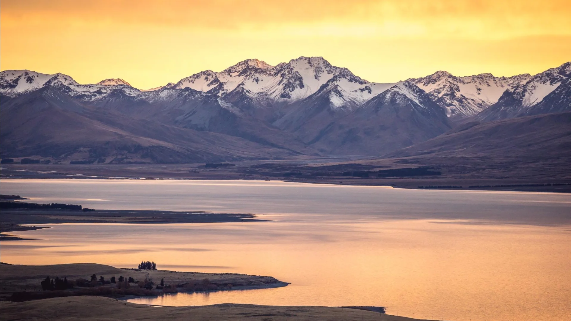 Zonsondergang bij Lake Tekapo met bergen die het meer omringen in Nieuw-Zeeland