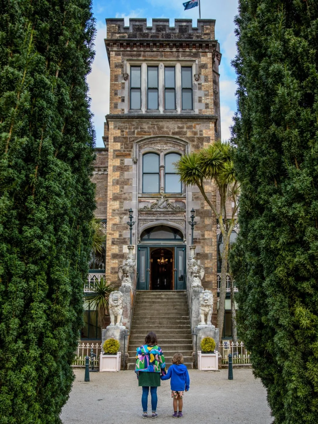 Moeder en kind staan voor de entree van Larnach Castle op het Otago Peninsula bij Dunedin, Nieuw-Zeeland