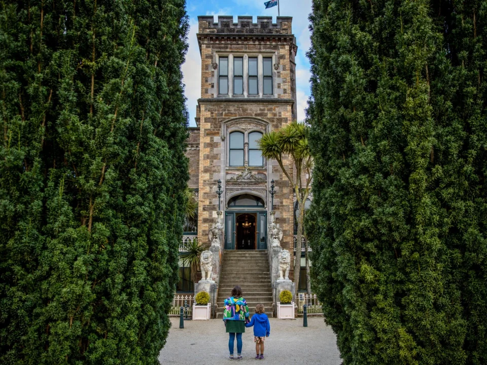 Moeder en kind staan voor de entree van Larnach Castle op het Otago Peninsula bij Dunedin, Nieuw-Zeeland