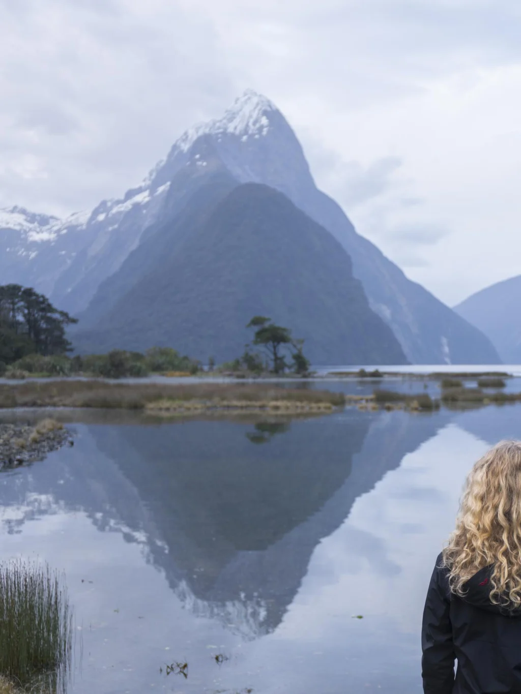 Vrouw kijkend naar Mitre Peak in de fjorden van Milford Sound