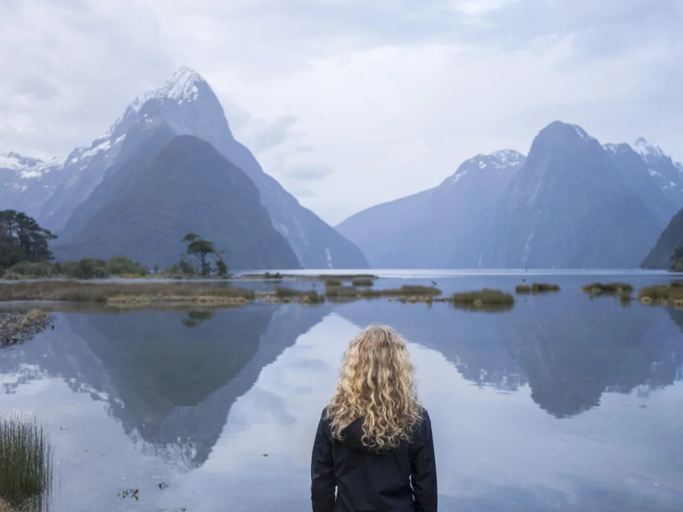 Vrouw kijkend naar Mitre Peak in de fjorden van Milford Sound