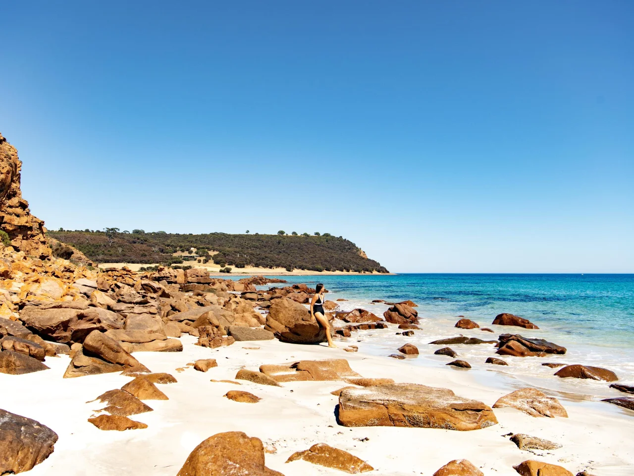 Vrouw leunend tegen de rotsen op het witte ongerepte strand van Emu Bay op Kangaroo Island