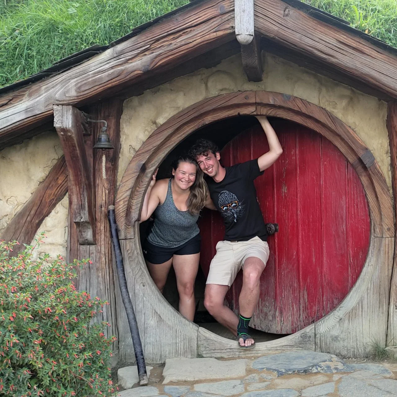 Judith en Bernard van opDroomreis.nu staat in de deuropening van een hobbit-huisje op de filmset van Hobbiton en Lord of the Rings in Matamata, Nieuw-Zeeland