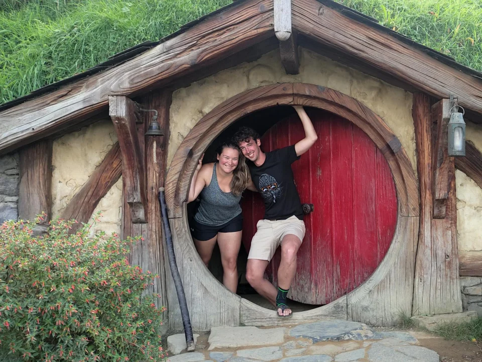 Judith en Bernard van opDroomreis.nu staat in de deuropening van een hobbit-huisje op de filmset van Hobbiton en Lord of the Rings in Matamata, Nieuw-Zeeland