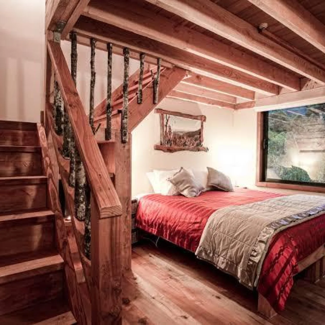 Slaapkamer met bed beneden en trap naar boven bij de Rough and Tumble Lodge