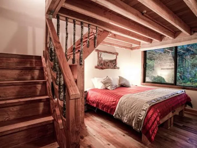 Slaapkamer met bed beneden en trap naar boven bij de Rough and Tumble Lodge