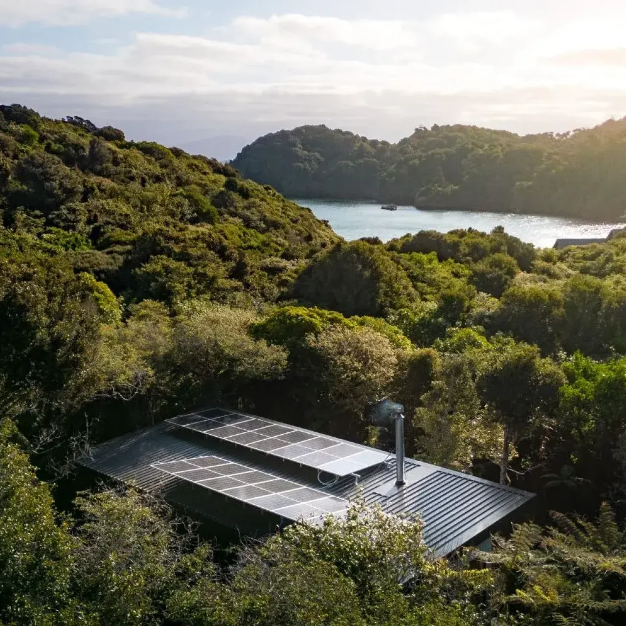 Ligging van Rakiura Cabins tussen het groen en met de baai in de verte, op Stewart Island, Nieuw-Zeeland
