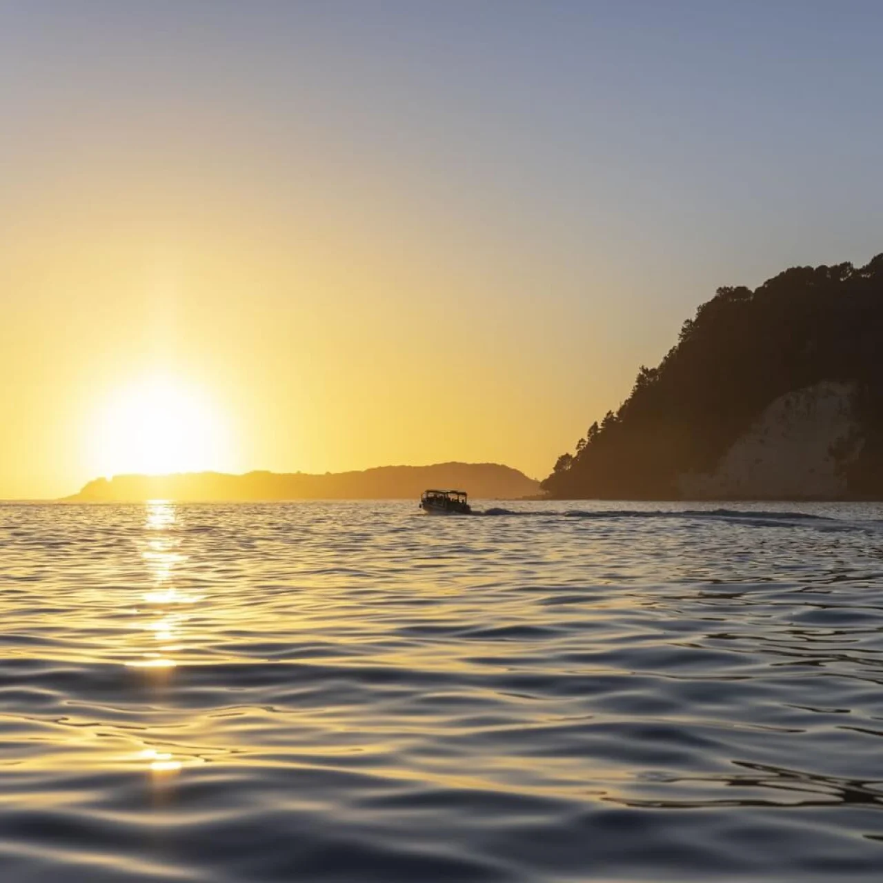 Zee met ondergaande zon en uitzicht op de eilanden bij Whitianga, Coromandel in Nieuw-Zeeland