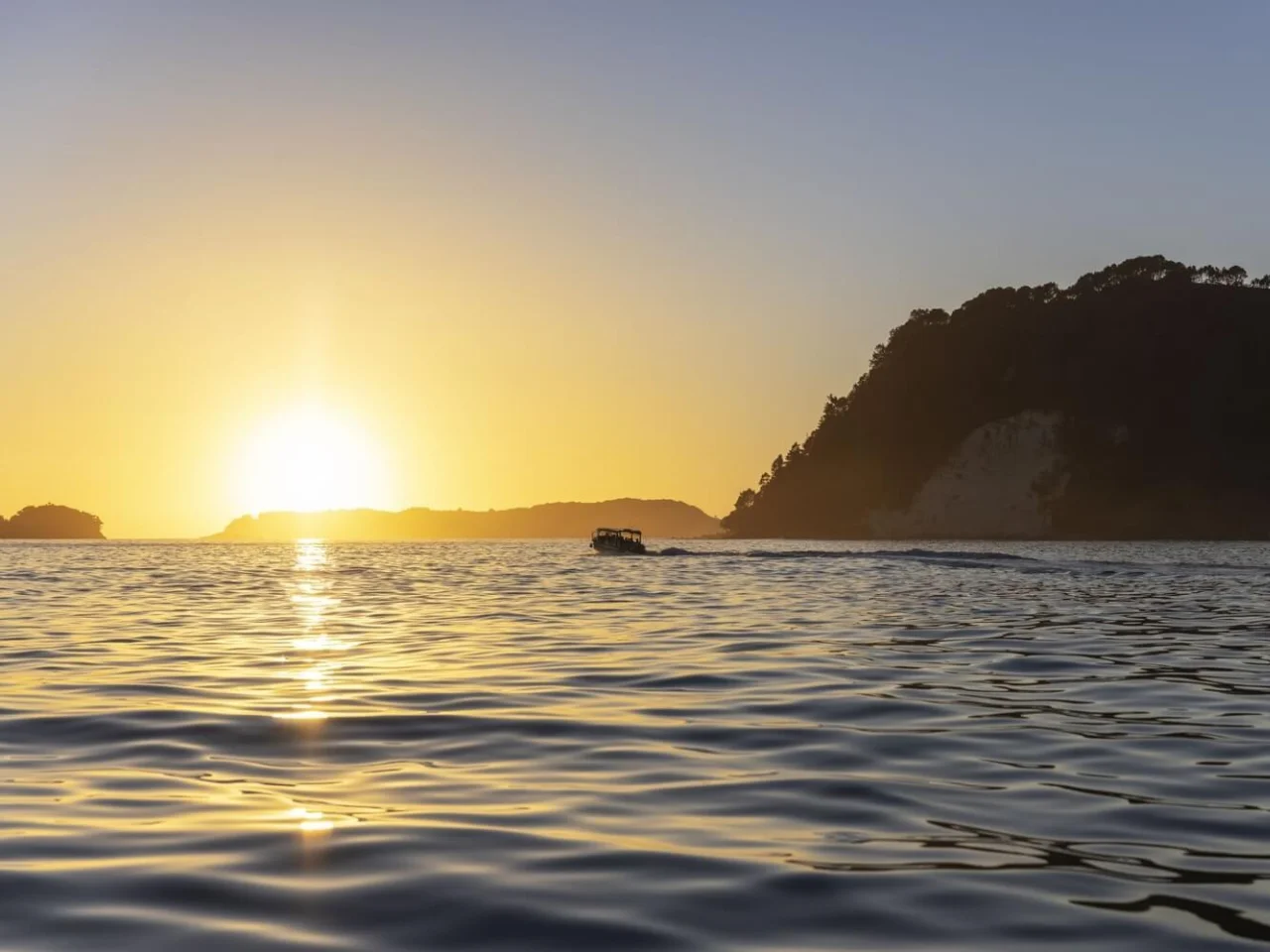 Zee met ondergaande zon en uitzicht op de eilanden bij Whitianga, Coromandel in Nieuw-Zeeland